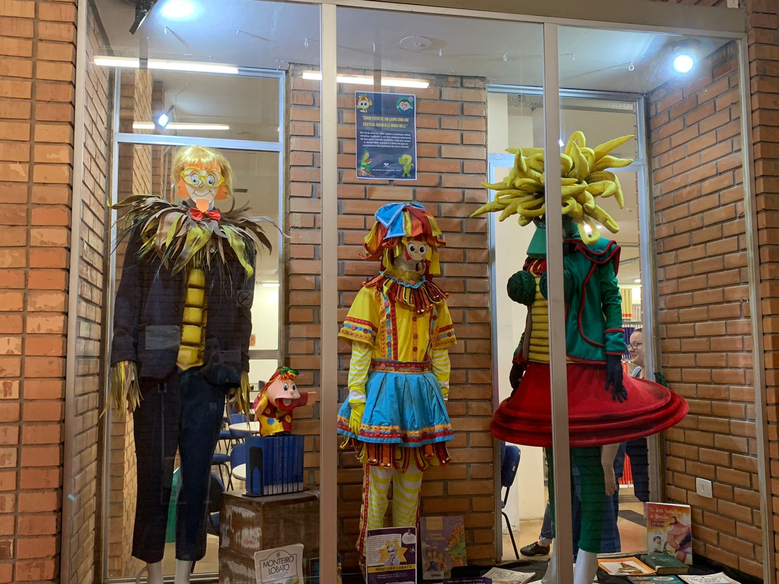 Foto de uma vitrine com 3 modelos não-humanos vestidos de roupas aleatórias representando a arte.